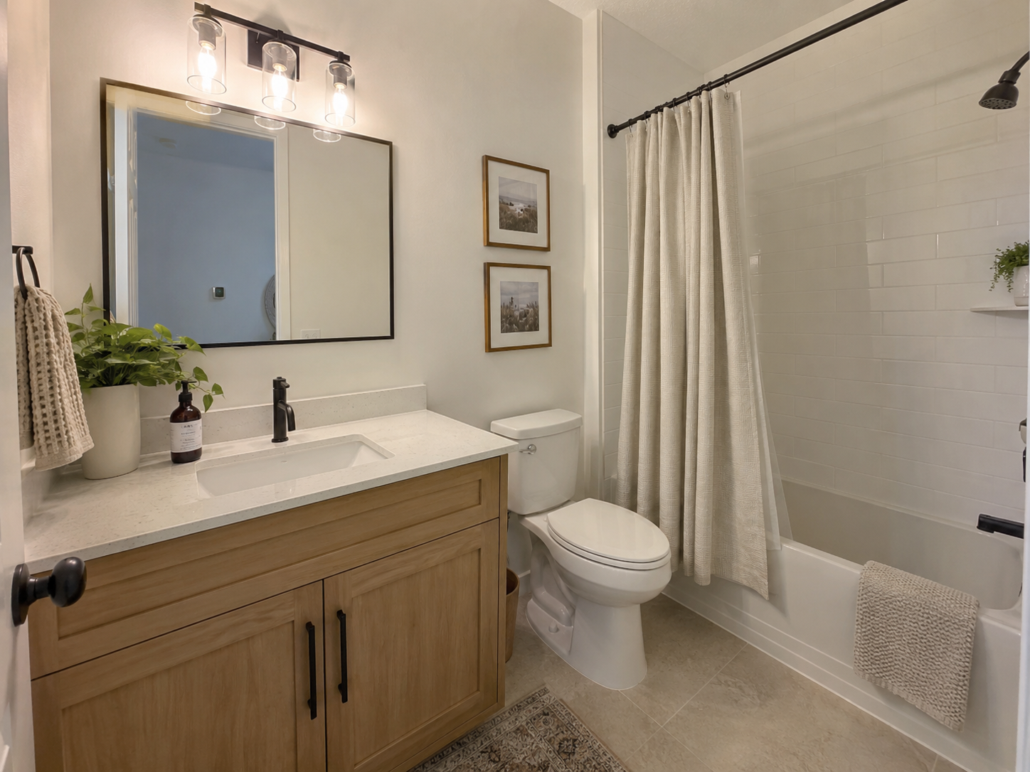 Small bathroom with oak vanity, black mirror, and textured beige shower curtain